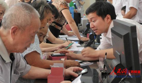 南昌市東湖區(qū)和市民政局工作人員向居家老人介紹專用手機(jī)如何使用。