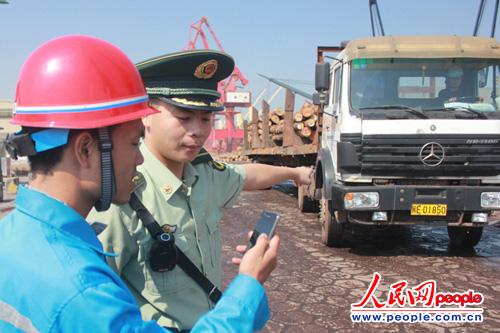 圖為執(zhí)勤人員正向碼頭工人現(xiàn)場演示政務(wù)微信智能管控功能（林錦瑜 攝）