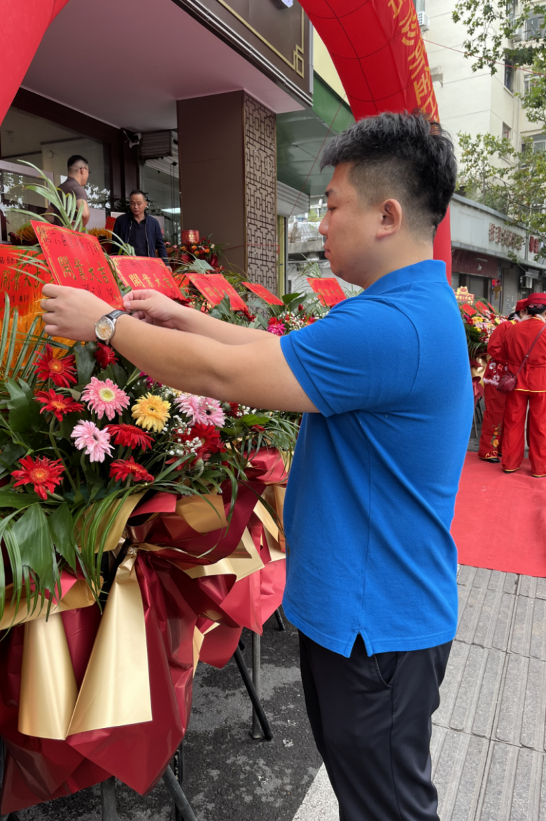 唐超群在整理朋友送來的開業(yè)花籃.png